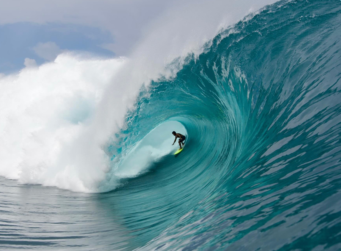 Surfer tucked deep in a turquoise barrel on a yellow Scovel board